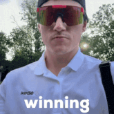 a man wearing sunglasses and a white shirt that says winning on it
