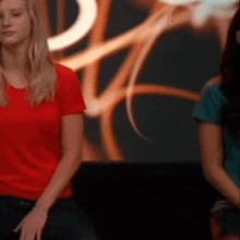 a woman in a red shirt sits next to another woman in a green shirt
