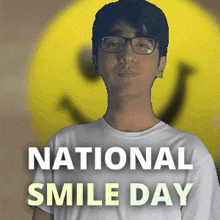 a man wearing glasses stands in front of a yellow smiley face with the words national smile day below him