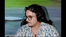 a man with glasses and a mustache is wearing headphones and a shirt .