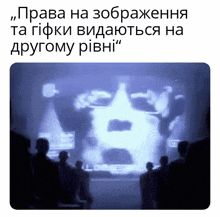 a group of people are looking at a screen with a face on it