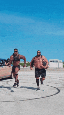 two men are running in a parking lot with one wearing a weighted vest