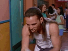 a man with long hair is standing in a hallway with a sign that says karate in the background