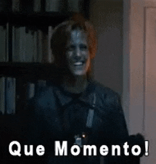 a man in a leather jacket is standing in front of a bookshelf and says que momento !