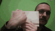 a man is holding a piece of paper in front of his face .