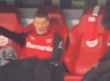 a soccer player is sitting in the stands wearing a red shirt .