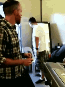a man in a plaid shirt stands next to another man