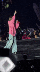 a woman in a pink shirt is singing into a microphone on stage