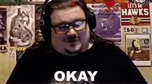 a man wearing headphones and glasses is sitting in front of a wall with posters .