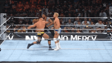 two men are wrestling in a ring with a sign that says no mercy on it