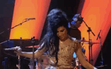 a woman singing into a microphone on a stage in front of a drum set