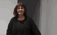 a woman with red hair is wearing a black sweater and a black shirt .