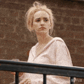 a woman in a pink hoodie stands on a balcony holding a glass of wine and a netflix logo