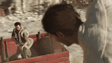 a man in a white shirt is standing next to a man in a red box