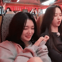 two girls are sitting on a bus with their eyes closed and one is smiling