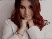 a woman with red hair is wearing a white shirt and silver bracelets