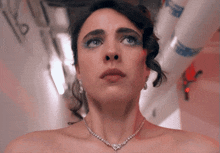 a woman wearing a necklace and earrings looks up at the camera