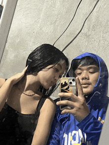a man in a blue hoodie takes a selfie with a woman