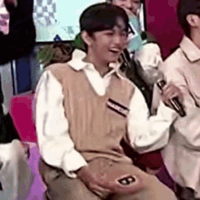 a man is sitting in a chair holding a microphone .