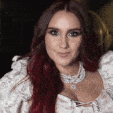 a woman with red hair is wearing a necklace of pearls