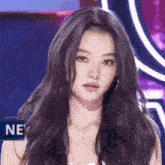 a close up of a woman 's face with long black hair and a purple background .
