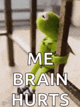 kermit the frog is sitting on a railing holding onto a railing .