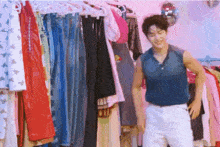 a man in a blue tank top is standing in front of a closet full of clothes