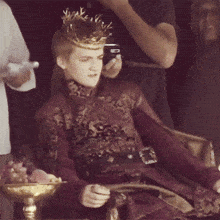 a man wearing a crown is sitting on a throne