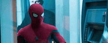 a close up of a person in a spiderman suit standing next to an atm machine .