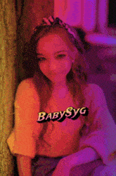 a girl leaning against a wall with babysyg written on the top