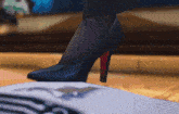 a woman wearing a pair of black high heels with red soles is standing on a piece of paper .