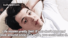 a man is laying on a bed with a quote about life moving fast .