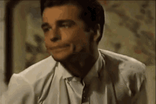 the man is wearing a white shirt and tie and making a funny face .
