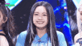 a girl in a blue shirt is smiling on stage