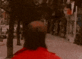 a man wearing glasses and a red jacket is walking down a street .