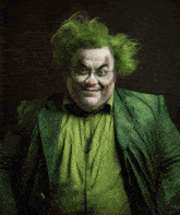 a clown with green hair and glasses is wearing a green jacket and green shirt