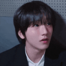 a close up of a young man 's face wearing a suit and a white shirt .