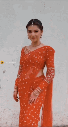 a woman is wearing a red saree and a gold necklace .