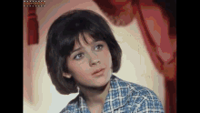 a young woman in a plaid shirt is looking at the camera .