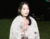 a woman wrapped in a plaid blanket waves