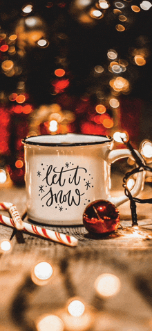 a mug that says let it snow is on a table