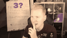 a man with his finger on his lips in front of a white board with the number 33 on it