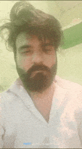 a man with a beard is wearing a white shirt and taking a picture