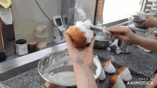a person is holding a donut with whipped cream on it in front of a bowl of whipped cream and the words made in animotica