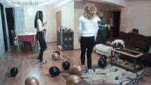 a group of people are dancing in a living room with balloons on the floor