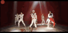 a group of people are dancing on a stage in front of a red light .