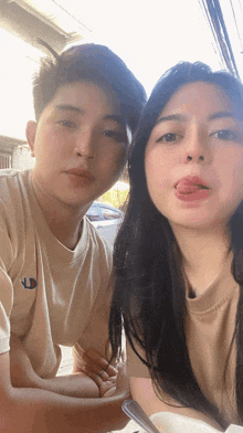 a man and a woman are posing for a picture with the woman sticking out her tongue