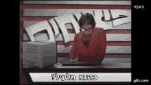 a woman in a red jacket is typing on a keyboard in front of a computer screen that says " gifs.com "