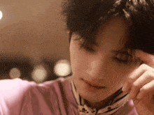 a close up of a person 's face with a pink shirt on .