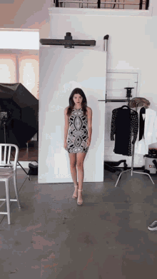 a woman in a dress is standing in front of a white board
